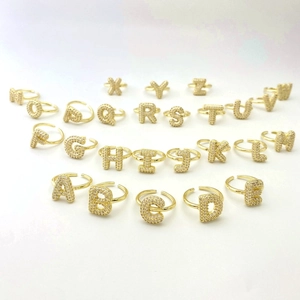 Detailed macro layout of 26 gold-plated letter rings featuring micro-set zircon accents
