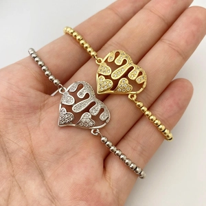 Detail of heart-shaped hollow charms with micro-zirconia on gold and silver beaded bracelets