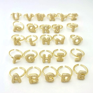 Detailed view of 26 gold-plated letter rings with pave cubic zirconia on white surface