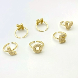 Detailed shot of gold-plated open rings with micro-paved cubic zirconia letters K, M, V, L