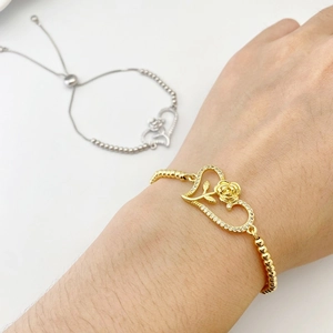 Close-up of heart-shaped bracelet with rose engraving and cubic zirconia in gold and silver