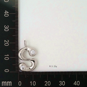 Close-up of letter S pendant with zircon stones showing dimensions on a scale ruler