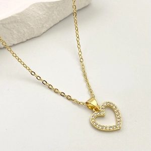Dettaglio del ciondolo a cuore dorato con micro-pavé di zirconi e catenina a maglie classica