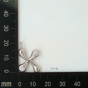 Detail view of a silver cross pendant with clear cubic zirconia on a measuring ruler