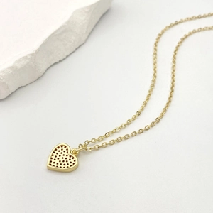 Vista macro del ciondolo a cuore in oro 18K con dettagli micro-pave su catena fine