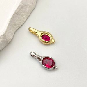 Dettaglio di ciondoli oro e argento con pietre rosse ovali e finitura in metallo martellato