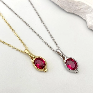 Dettaglio di collane in oro e argento con pietre rosse a cuore e texture martellata