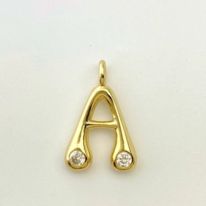 Close-up of golden letter A pendant with sparkling cubic zirconia on white background