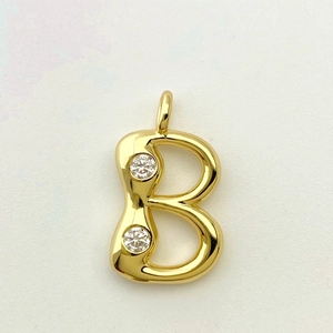 Detailed view of golden letter B pendant with double cubic zirconia inlay and polished finish