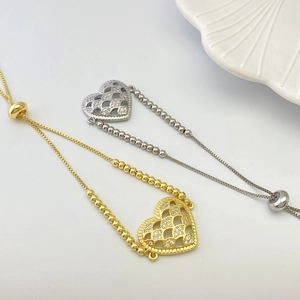 Detail of gold and silver heart bracelets with zircon inlay and adjustable bead sliders