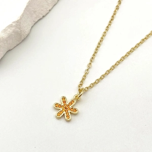 Dettaglio della collana dorata con ciondolo a fiore in zirconi arancioni micro-pavé