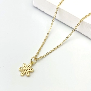 Dettaglio del ciondolo a fiore in oro 18K con design traforato e finitura in rame lucido