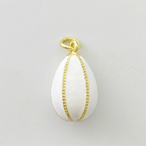 Vue détaillée du pendentif œuf en émail blanc avec lignes dorées et perles