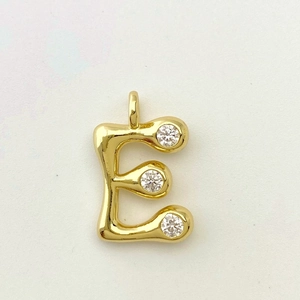 Detail of a polished gold letter E pendant featuring three sparkling zircon stones
