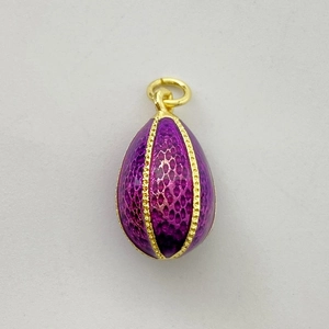 Vue macro du pendentif œuf en émail violet avec texture écailles dorée et bordure