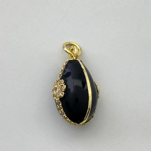 Détail macro d'un pendentif œuf en émail noir avec bordure dorée et petits cristaux
