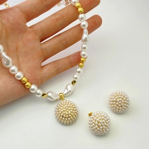 Close-up of pearl bead necklace and matching stud earrings with gold accents
