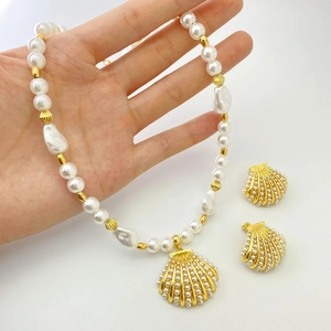 Detailed close-up of shell necklace and earring set featuring gold scallops and pearls