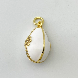 Macro d'un pendentif en forme d'œuf avec émail blanc, bordure dorée et cristaux brillants