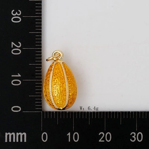 Vue détaillée du pendentif œuf doré avec texture nid d'abeille et mesure de 22 mm