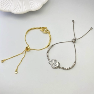 Detail of gold and silver heart bracelets featuring cubic zirconia and adjustable slide clasp