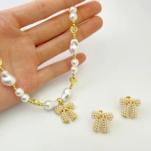 Detailed view of handmade pearl necklace and earrings set with gold bow pendants