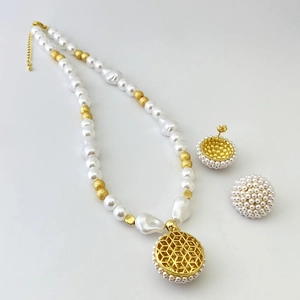Detailed shot of pearl necklace set with golden honeycomb pendant and shell beads