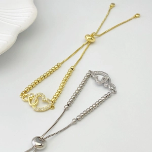 Detail of adjustable gold and silver bracelets with cubic zirconia heart and infinity charm