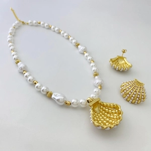 Detail of shell-shaped gold earrings and pearl necklace with baroque ocean charms
