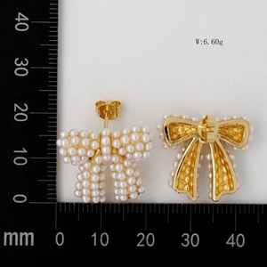 Bow-shaped pearl earrings with gold metal backing and measurement scale reference