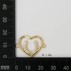 Macro view of a gold heart charm with horseshoe zircon inlay and measurement scale