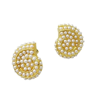 Golden snail shell earrings set with white pearls on a minimalist white background