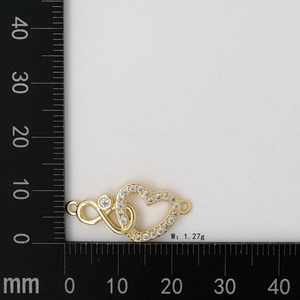 Macro view of a gold heart and infinity symbol connector link with 20mm ruler