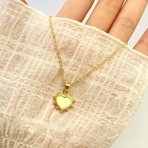 Close-up of heart-shaped gold pendant necklace with radiant sunburst texture details