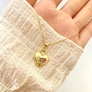 Macro view of gold heart lock pendant with I love you stones on white fabric