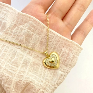 Detail of gold heart pendant with micro-paved zircons on a delicate chain necklace