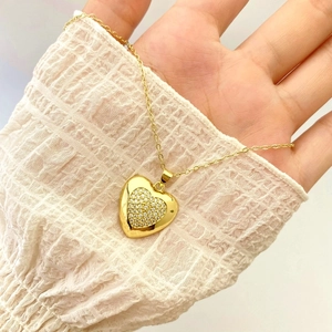Detail of gold heart pendant necklace featuring nested design and cubic zirconia pavé