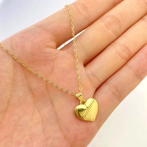 Detail of gold heart pendant with baseball stitching texture on thin chain