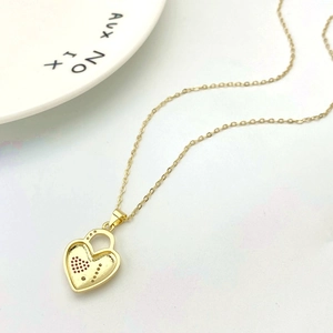 Macro shot of gold heart-lock pendant necklace on a clean white aesthetic background