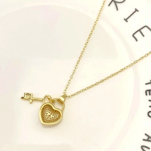 Detail of gold heart lock and key pendant with hollow honeycomb pattern on the back