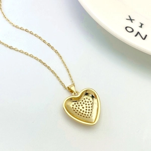 Macro view of gold heart pendant showing premium honeycomb cutout detail and fine craftsmanship