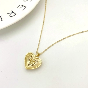 Macro detail of gold heart pendant with cubic zirconia and honeycomb back design
