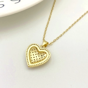 Close-up of golden heart pendant featuring intricate beaded edges and honeycomb back details