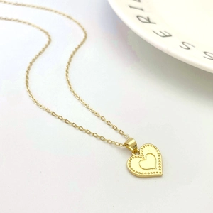 Close-up of golden double heart pendant necklace with dotted border on white background