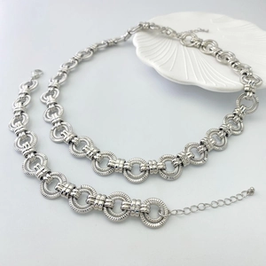 Détail du collier et bracelet en chaîne argentée avec anneaux texturés sur plateau