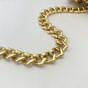 Detail einer klobigen goldenen herzförmigen Metallkette mit poliertem Spiegelglanz für Taschen