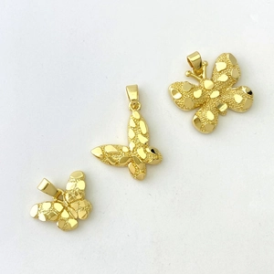 Detailed macro of three different sized 18K gold butterfly pendants with textured finish