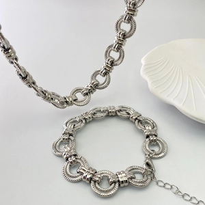 Détail de la parure de bijoux en chaîne argentée avec texture industrielle et fermoir