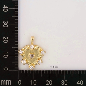 Close-up of golden heart pendant with zircons measured on a millimeter ruler