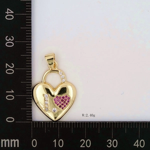 Macro detail of gold heart padlock pendant with zircon inlay measured on a ruler